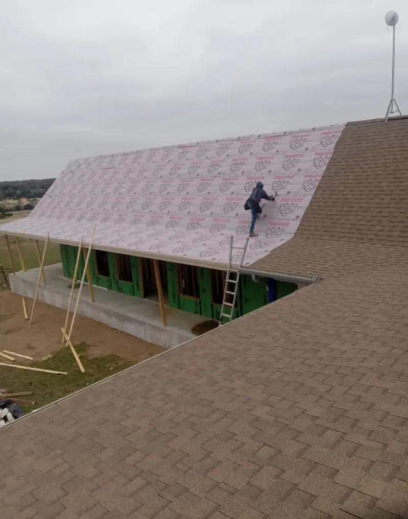 Worker preparing underlayment for a metal roof installation in Hornsby Bend